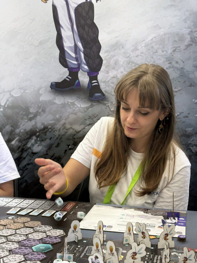 Ritratto di Debora Cavazzoni Visual Designer - Graphic & Ux Designer seduta ad un tavolo da gioco che lancia i dadi